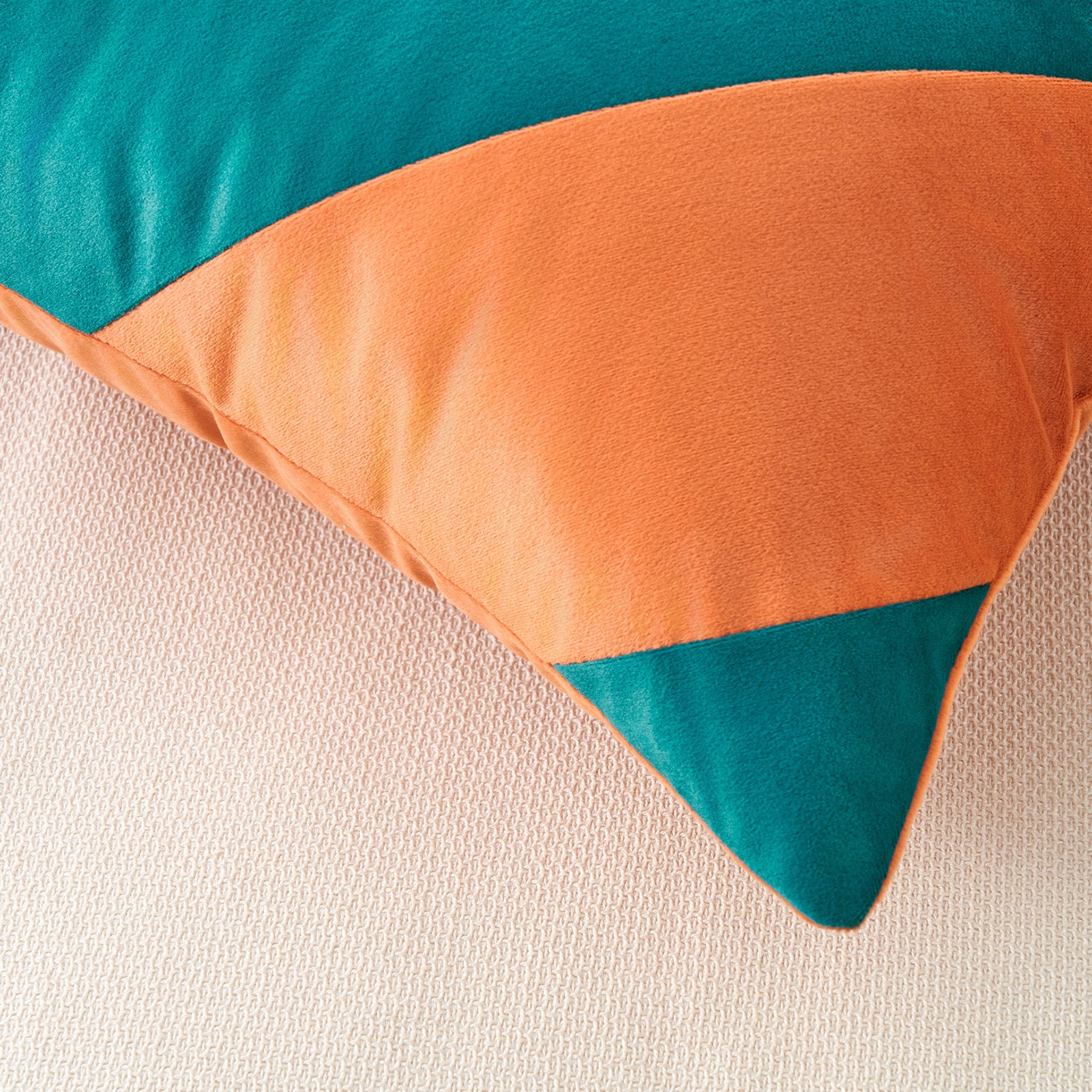 Color-blocked pillow with teal and orange on a beige background