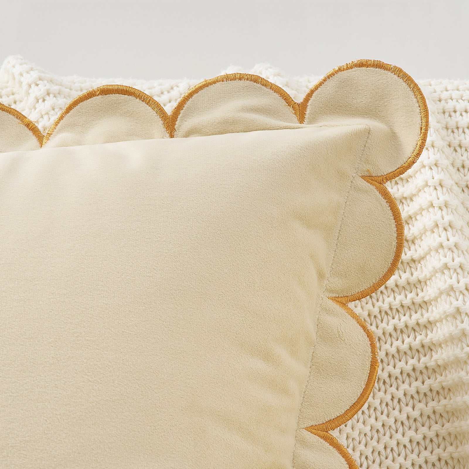 Beige pillow with scalloped edge on a textured beige background