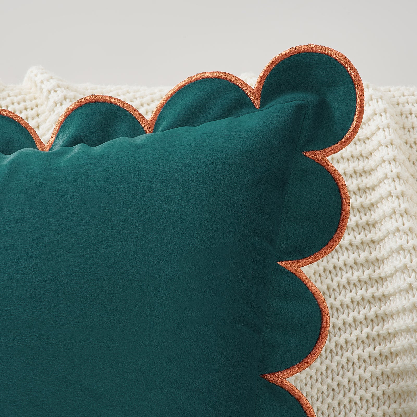Teal pillow with scalloped edge on a textured beige background