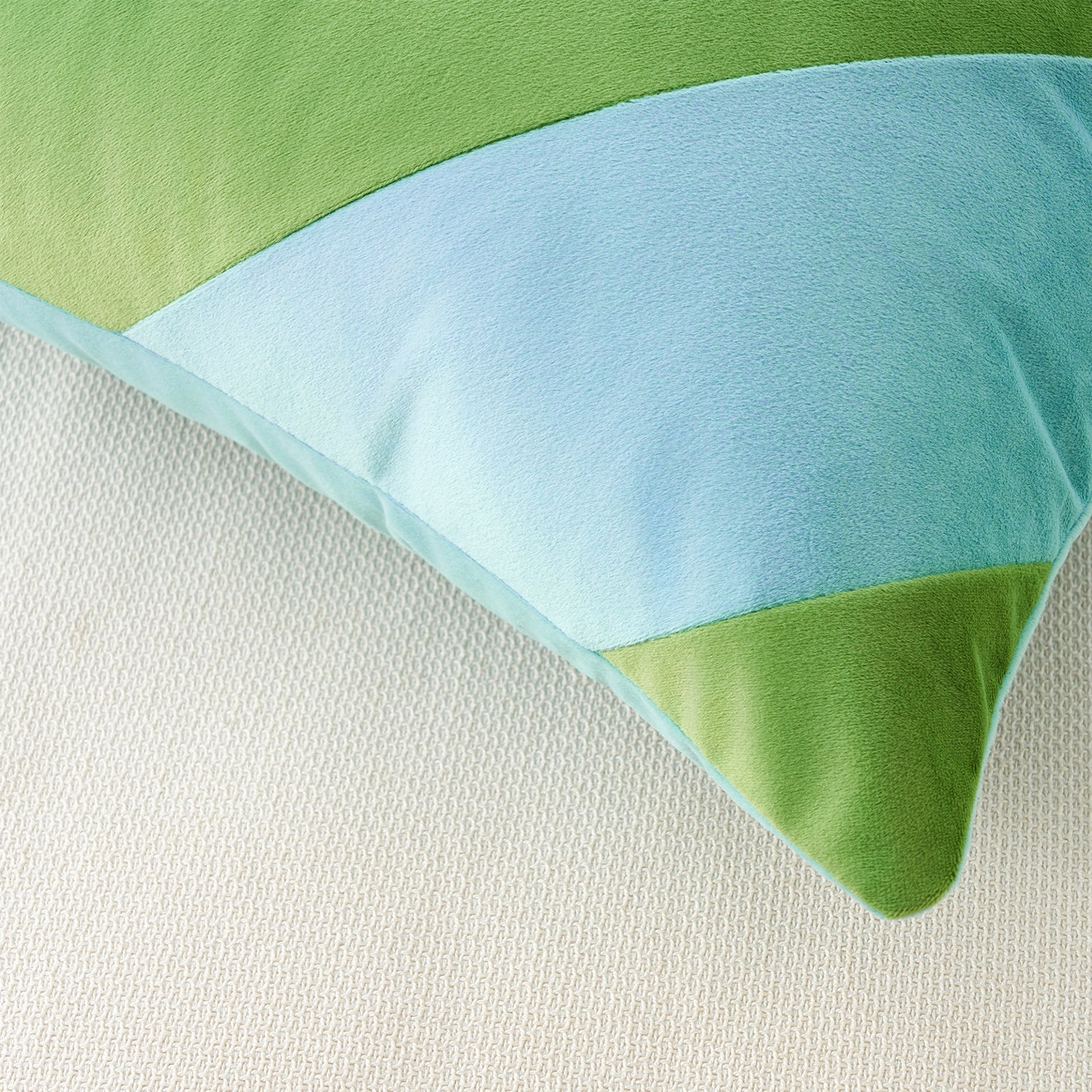 Close-up of a green and blue striped pillow on a textured surface