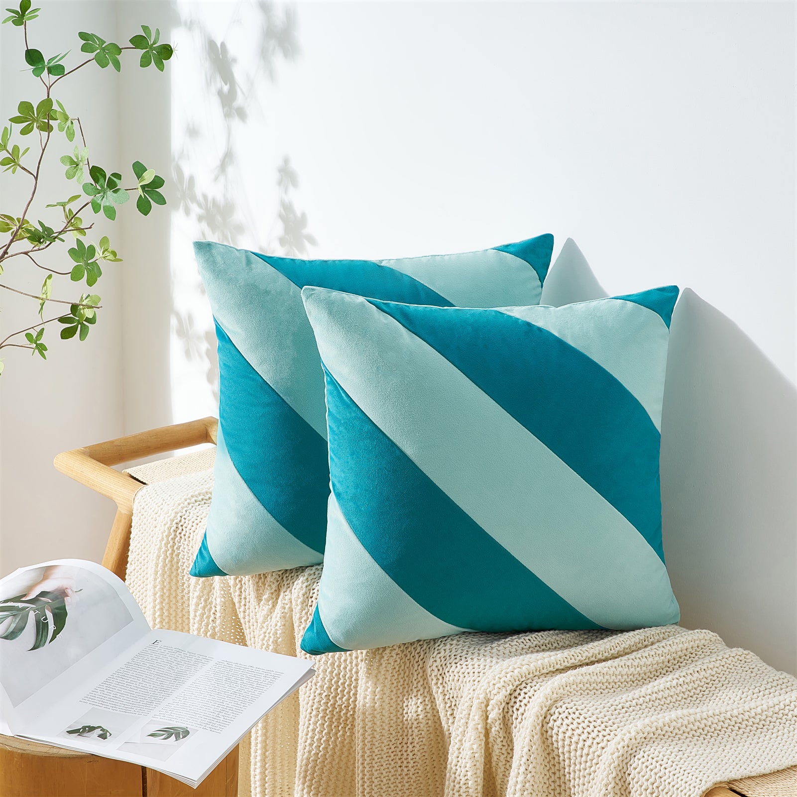 Teal and light blue striped pillows on a beige surface with a plant in the background