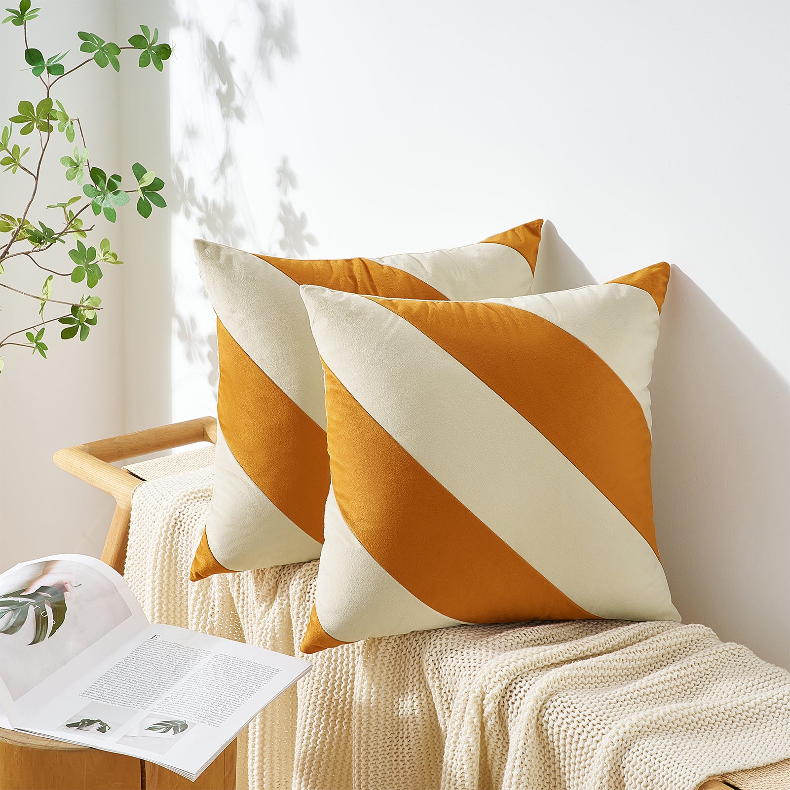 Orange and white striped pillows on a wooden chair with a plant in the background