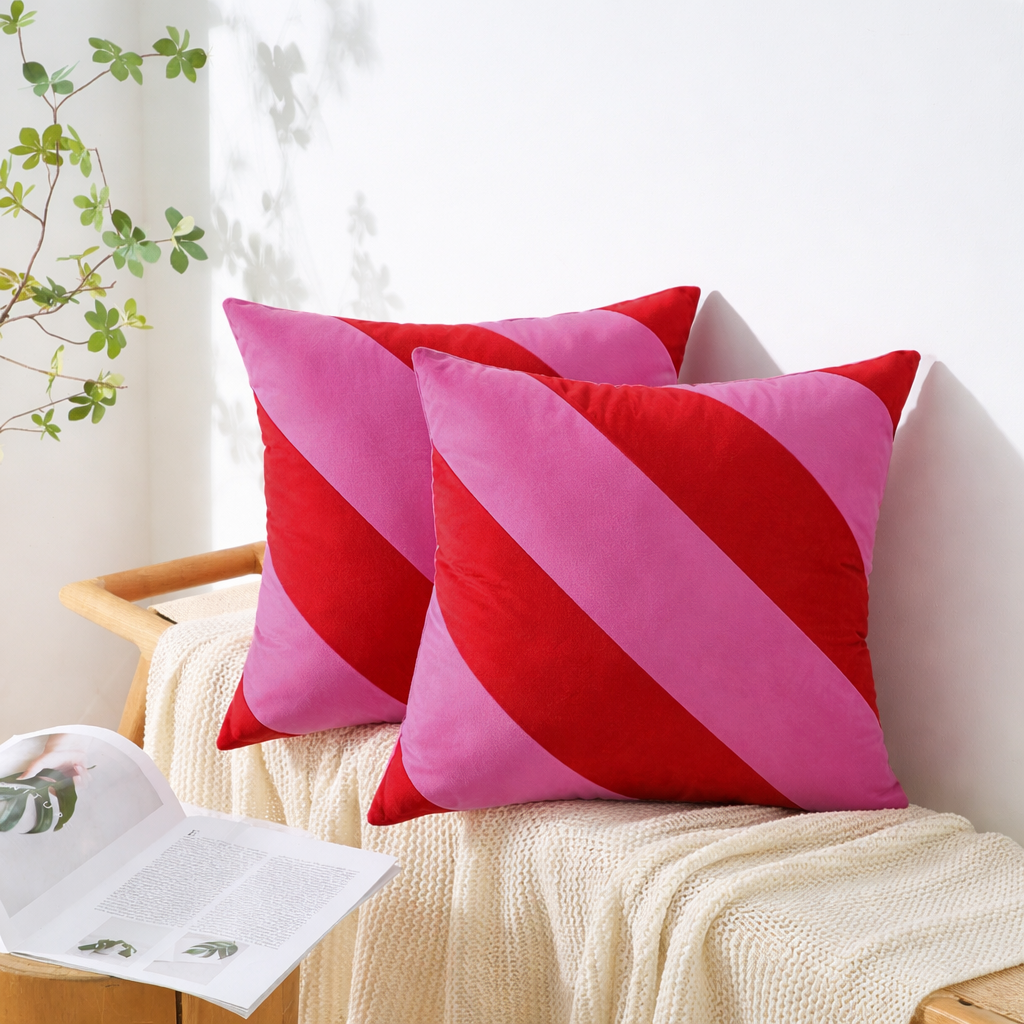 Pink and red striped pillows on a white couch with a plant in the background
