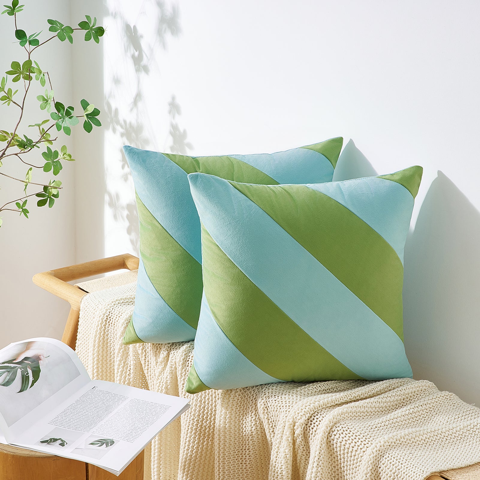 Green and blue striped pillows on a white surface with a plant in the background