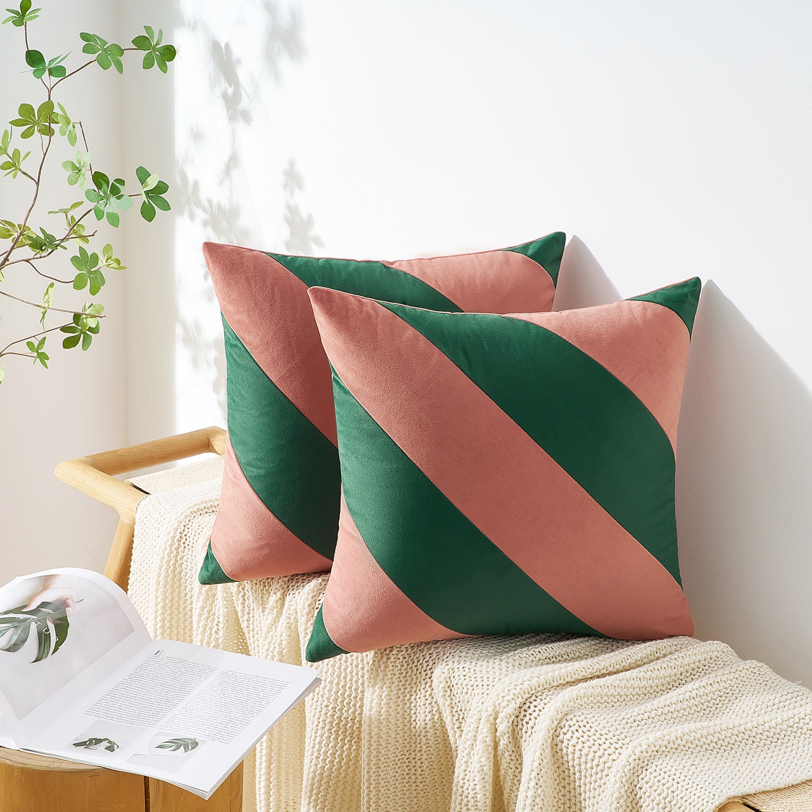 Pink and green striped cushions on a white sofa with a plant in the background