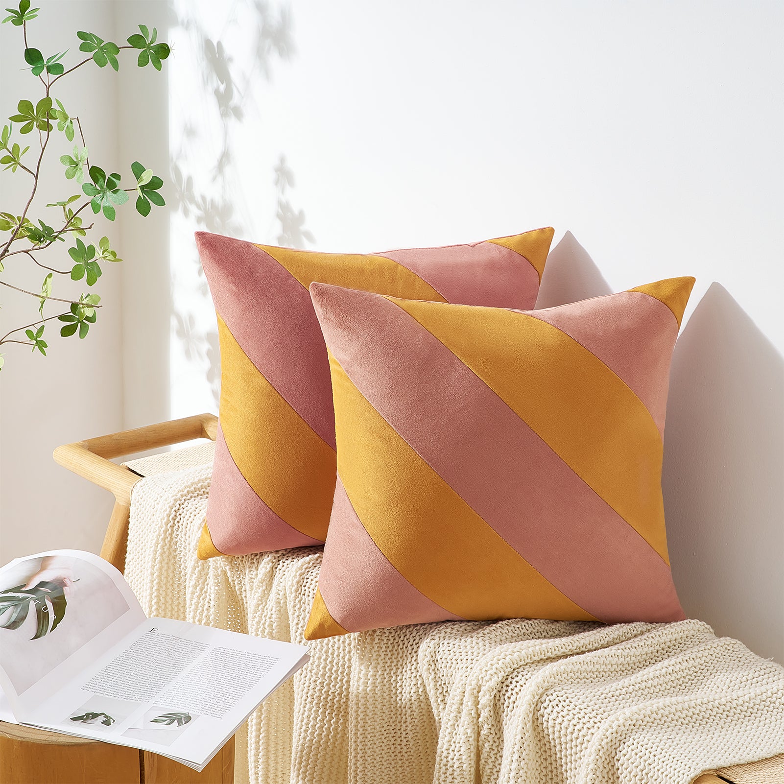 Two decorative pillows with pink and yellow diagonal stripes on a white couch.
