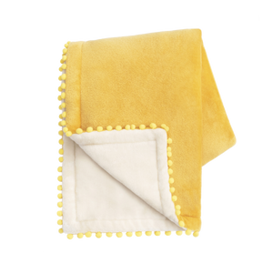 Yellow blanket with pom-pom trim on a white background