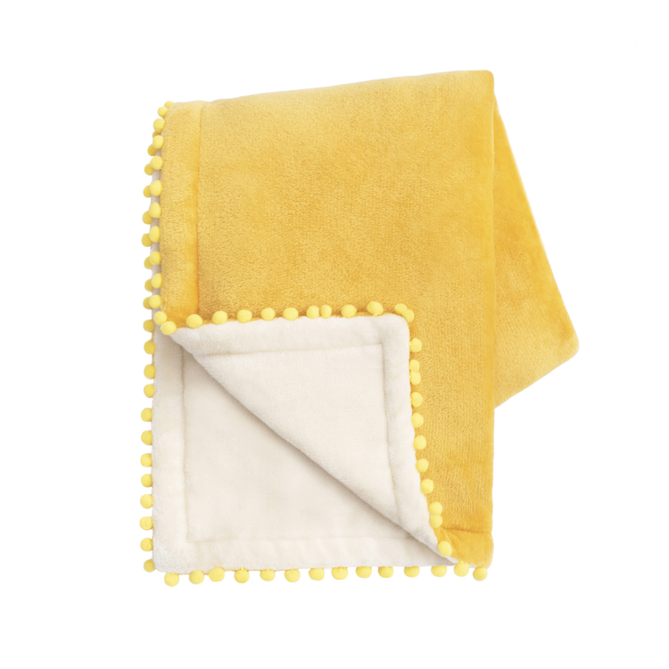 Yellow blanket with pom-pom trim on a white background